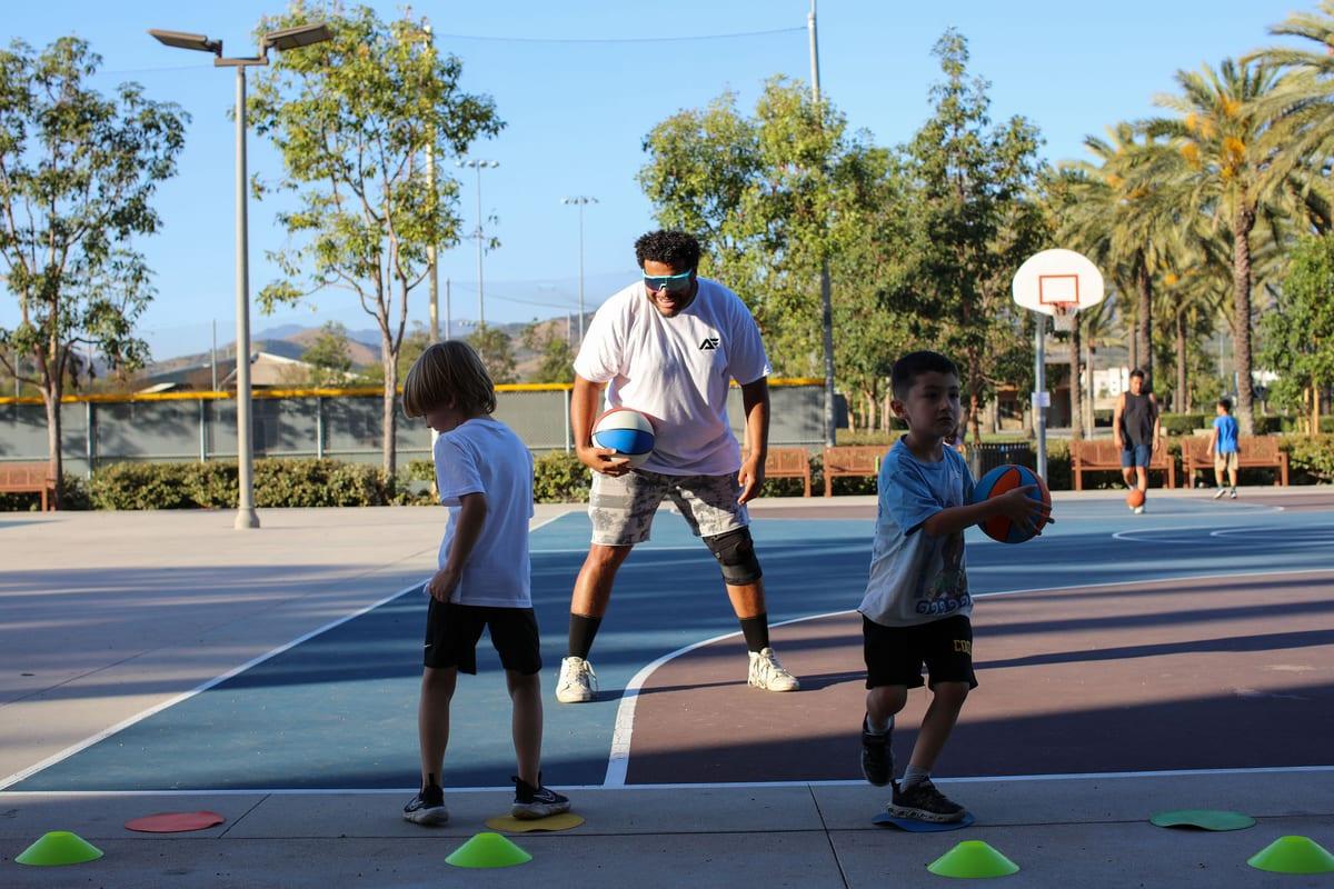 Coach Mike running a basketball drill with two young athletes on the court