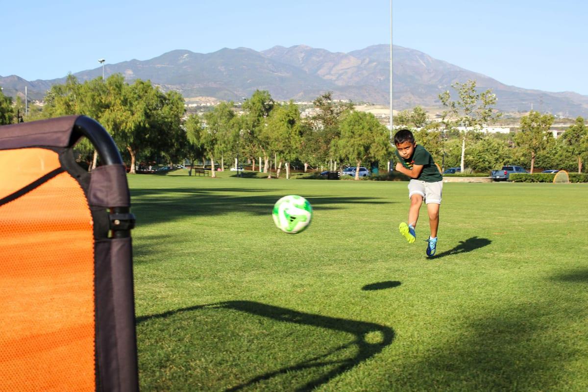 A young AFC athlete striking the ball with the Orange County mountains behind