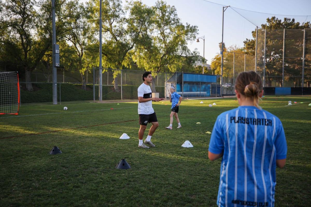 An AFC coach leading a golden-hour training session with young athletes