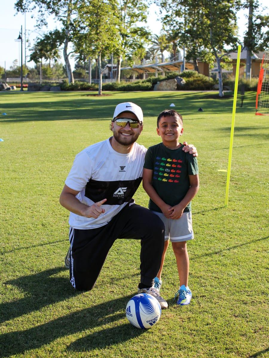 An AFC coach kneeling beside a young athlete after training